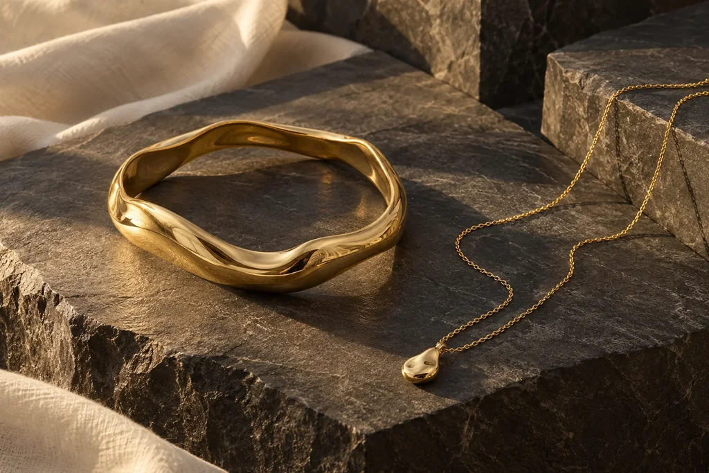 Sculptural gold jewellery resting on charcoal mineral stone